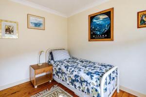 a small bedroom with a bed and a night stand at Waterfront Delight on Cater in Sussex Inlet