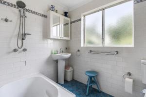 a white bathroom with a tub and a sink and a sink at Waterfront Delight on Cater in Sussex Inlet +14 photos