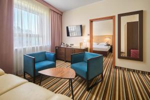 a hotel room with a couch and chairs and a bed at Hotel Victor Pruszków DeSilva in Pruszków
