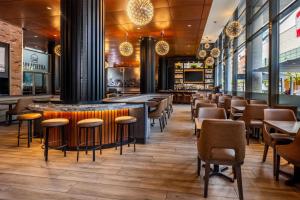 a restaurant with chairs and tables and a bar at Embassy Suites by Hilton - Montreal in Montreal