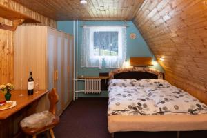 a bedroom with a bed and a table and a window at Horská chata LADA in Loučná pod Klínovcem
