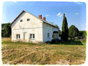 an old white house sitting in a field at Chalupa nad Dvorem in Slezské Pavlovice