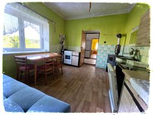a kitchen with a table and a kitchen with green walls at Chalupa nad Dvorem in Slezské Pavlovice