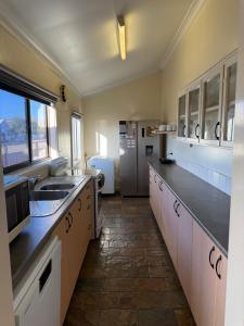 a large kitchen with white cabinets and a refrigerator at Lake Macquarie holidays in Marks Point