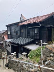 a black house with a porch and a roof at NouHarborVilla in Itoigawa