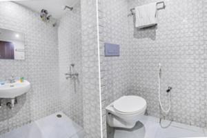 a white bathroom with a toilet and a sink at FabHotel Maple Leaf in Hyderabad