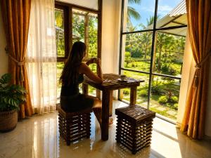 a woman sitting at a table in front of a window at The Ramp Udawalawe in Udawalawe