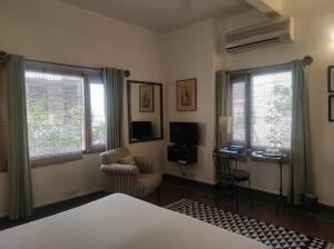 a bedroom with a bed and a chair and windows at Zaza Stay in New Delhi