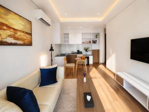 a living room with a white couch and a kitchen at One Studio Suite by PSH in Krong Poi Pet