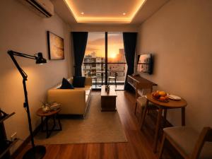a living room with a couch and a large window at One Studio Suite by PSH in Krong Poi Pet