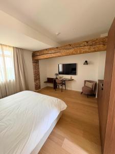 ein Schlafzimmer mit Bett, Schreibtisch und Fernseher in der Unterkunft Hôtel Éole Resort - Mons - Shape - Pairi Daiza in Warchaix