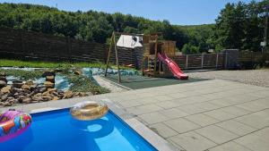 a backyard with a pool with a slide and a playground at Wisienka in Pstrągowa