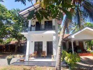 a white house with a palm tree in front of it at Ken Homestay Waikkala in Wayikkal