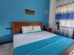 a bedroom with a bed with a blue wall at Ken Homestay Waikkala in Wayikkal