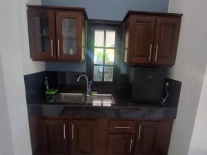 a kitchen with wooden cabinets and a sink and a window at Ken Homestay Waikkala in Wayikkal