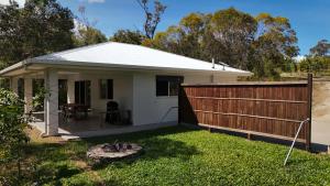 a small white house with a wooden fence at Koah hideaway cottage in Koah