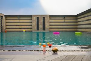 a pool with three drinks and a frisbee in the water at Savoy Suites Manesar in Gurgaon