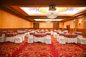 a banquet hall with tables and chairs and a chandelier at Savoy Suites Manesar in Gurgaon +34 photos