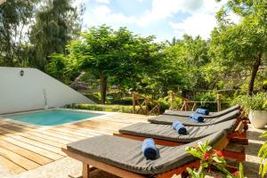 three chaise lounges on a deck next to a swimming pool at Pongwe Beach Hotel in Pongwe