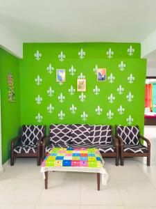 a room with a couch and a green wall with white flowers at Elite Calangute Beach Holiday Apartments With Pool in Calangute