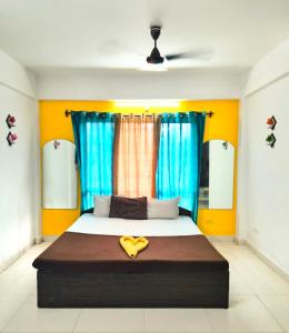 a bedroom with a large bed with blue curtains at Elite Calangute Beach Holiday Apartments With Pool in Calangute
