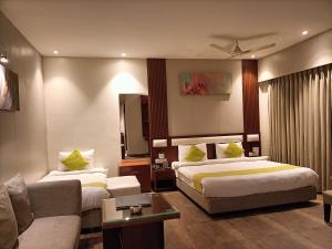 a hotel room with two beds and a couch at Club Central in Bolpur