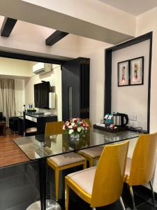a dining room with a glass table and yellow chairs at Ramee Guestline Hotel Khar in Mumbai