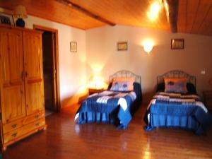 a bedroom with two beds and a wooden floor at Le Logis de bouillé in Bouillé-Courdault