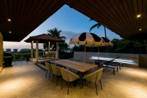 a wooden table and chairs with umbrellas on a patio at Katamanda Aliya Pool & Jacuzzi Villa Kata in Kata Beach