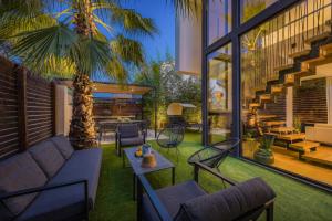 a patio with a couch and chairs and a palm tree at Luxury TABOO Villa & Spa in Medulin for 8 people with heated pool & wellness area in Medulin +57 photos