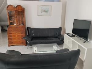a living room with a black leather couch and a television at Traumhafte Lage am Kurpark in Bad Nauheim