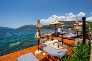 a wooden deck with chairs and umbrellas and a boat at Ollie's by the sea in Donja Lastva +127 photos