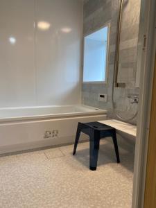 a bathroom with a black stool in front of a tub at NouHarborVilla in Itoigawa