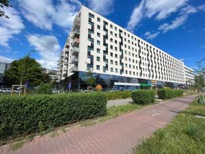 a large white building with a brick path in front of it at A very cozy apartment with a large bed in Wrocław