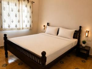 a bedroom with a bed with white sheets and a window at Vox Valavan in Mayiladuthurai