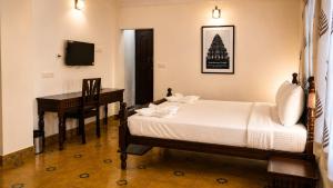 a bedroom with a bed and a desk and a television at Vox Valavan in Mayiladuthurai
