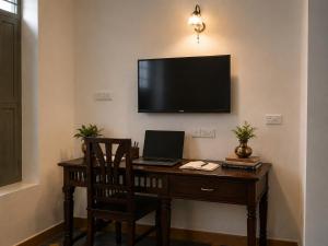 a desk with a laptop and a television on a wall at Vox Valavan in Mayiladuthurai