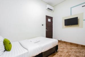 a small room with a bed and a tv at Urbanview Hotel Aloevera Pontianak by RedDoorz in Pontianak