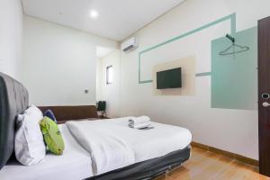a hotel room with a bed and a tv at Urbanview Hotel Aloevera Pontianak by RedDoorz in Pontianak