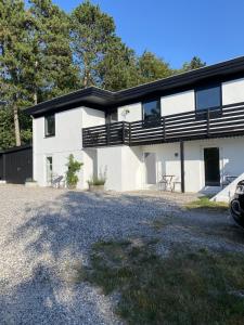 a white house with black balconies and a driveway at Overnatning Egsmark in Ebeltoft