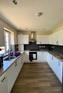 a kitchen with white cabinets and a sink at Enyo House Brentford London in Brentford