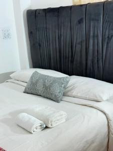 a bed with white sheets and a blue pillow on it at Airport Lodge Hotel in Kempton Park