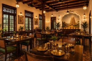 a restaurant with tables and chairs and a painting on the wall at Vox Valavan in Kuttālam