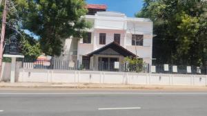 a white house on the side of a street at Vox Valavan in Kuttālam