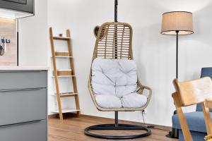 a rattan chair in a living room with a lamp at Apartmány s výhledem na Plešivec by Mountain ways in Abertamy