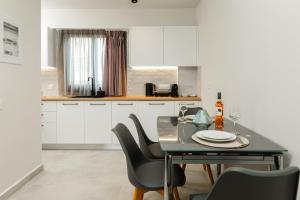 a kitchen with white cabinets and a table and chairs at Petra Suites Tolo in Tolo