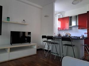 ein Wohnzimmer mit Küche, Fernseher und Stühlen in der Unterkunft Agrippa 24 in Mailand