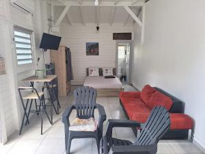 a living room with a red couch and two chairs at Terrasson GOLD2 in Les Abymes