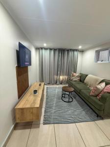 a living room with a green couch and a table at Cambridge Boutique Stay in Chiselhurst +3 photos