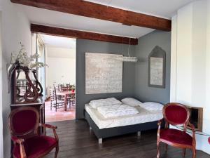 a bedroom with a bed and two red chairs at Appartement Overcinge in Havelte